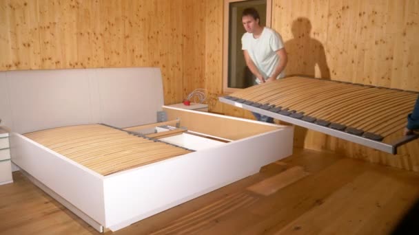 CLOSE UP: Young Caucasian couple hugs after assembling their king sized bed. — Stock Video