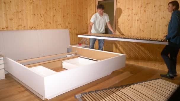 ZAMKNIJ SIĘ: Mężczyzna i kobieta zamontować deski bunkie na ramie łóżka duże łóżko. — Wideo stockowe