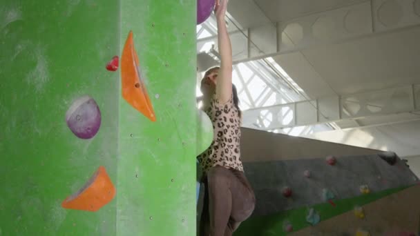 閉じる:フィット若い女性は晴れた日に屋内ボルダリングジムで登る. — ストック動画