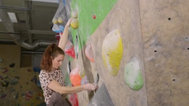 Genç bir kadın, kayalık spor salonunda antrenman yaparken zorlu bir yola giriyor..