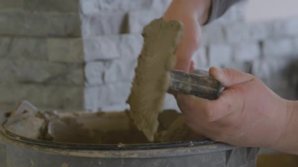 CHIUSURA: Tiler utilizza una spatola per applicare cemento a una parete durante la posa di piastrelle. — Video Stock