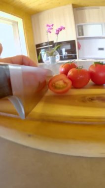 Tahta kesme tahtasındaki organik domatesleri dilimler..