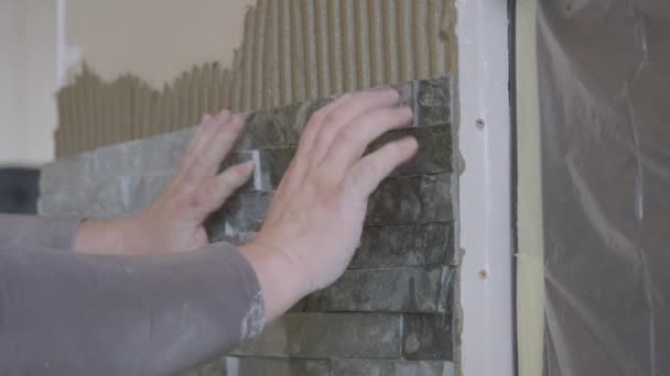 CLOSE UP: Unrecognizable tiler fits a natural stone tile on the living room wall — Stock Video