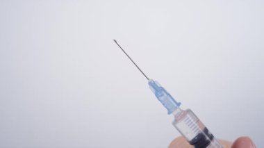 Keskin paslanmaz çelik bir iğne boyunca berrak sıvı damlacıkları süzülür..