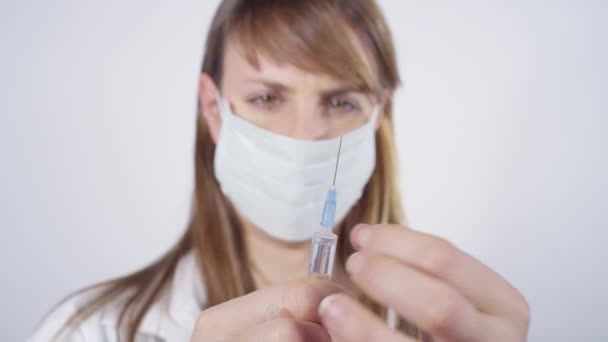 CERRAR: La enfermera joven que lleva una mascarilla facial prepara una jeringa para la vacunación. — Vídeo de stock