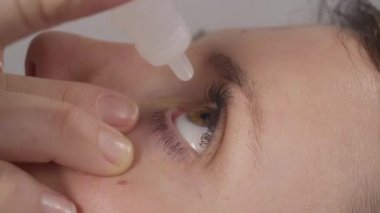 Yetişkin beyaz kadın, kuru sol gözünün içine göz ilacı atıyor..