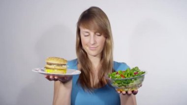 Kadın, öğle yemeği seçeneklerini tartarken salatayı hamburgere tercih ediyor..