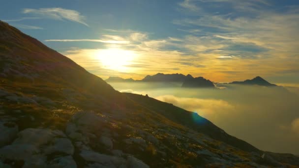 AERIAL: Latanie nad pustymi łąkami wysoko nad chmurami w Alpach złotego światła. — Wideo stockowe