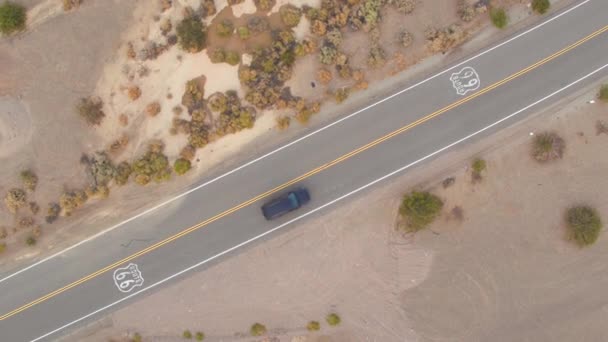 TOP DOWN: Voando acima da Rota 66 como carro solitário dirige ao longo da estrada reta — Vídeo de Stock