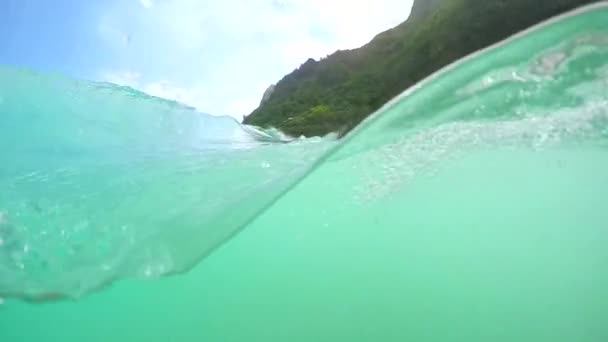 HALBUNDERWATER: Türkisfarbenes Wasser bricht in Richtung tropischer Sandstrand auf Hawaii. — Stockvideo