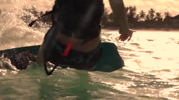 CLOSE UP: Fit woman kiteboarding in Tanzania splashes crystal clear ocean water. — Vídeos de Stock