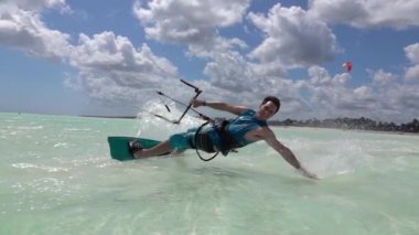 CLOSE UP: Happy man kiteboarding in Tanzania drags his hand along glassy ocean
