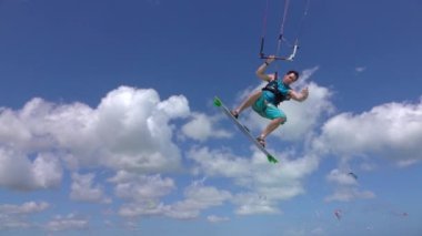 PORTRAIT: Kiteboarder jumping over the camera, showing shaka hang loose sign.