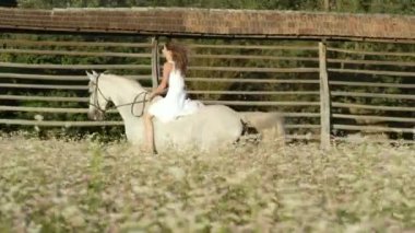 SLOW MOTION: Long haired woman riding bareback gallops on her white stallion.