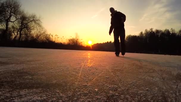 LOW Kąt: mężczyzna łyżwiarz obraca się i rozpyla lód do kamery o zachodzie słońca. — Wideo stockowe