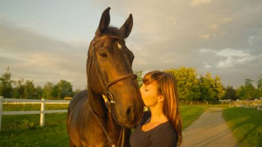 Neşeli genç kadın gözlerini kapar ve aygırını ağızlık ile öper..