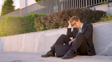 LENS FLARE: Young Caucasian man shakes his head in disbelief after losing job.