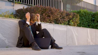 Pessimistic businessman buries his head in his hands after losing his dream job.