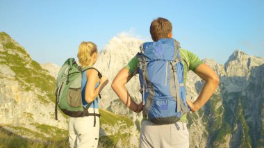 CLOSE UP: Unrecognizable trekkers observe the beautiful sunlit valley in Alps.