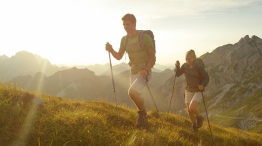 SUN FLARE: Happy woman and man enjoying a morning hike in the stunning mountains