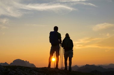 SUN FLARE: Golden morning sunbeams illuminate the hiker couple at the summit.