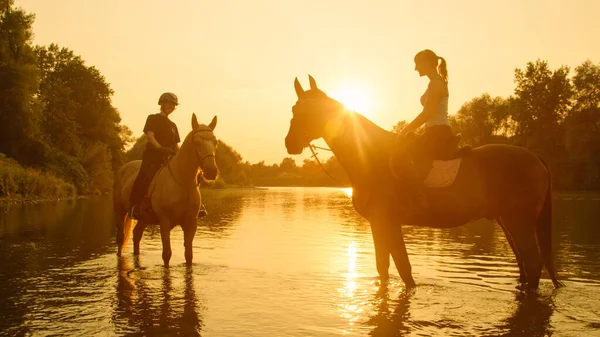 태양 광선: 개울을 따라 말을 타고 가는 여인들에게 아침 햇살 이비치고 있다. — 스톡 사진