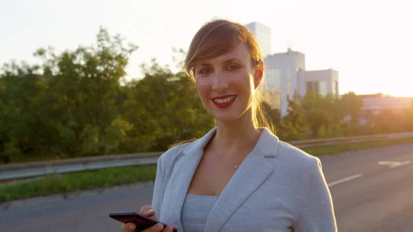 SUN FLARE: Cheerful elegant businesswoman smiles at camera while walking home. — стоковое фото