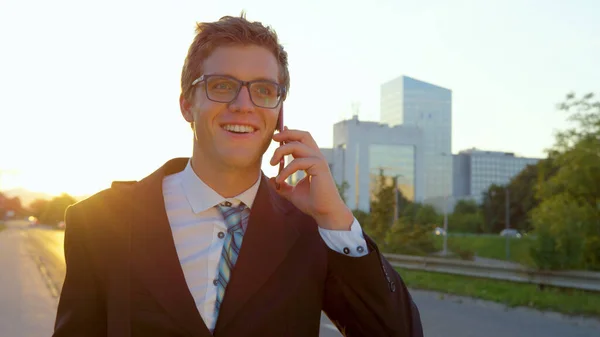 CLOSE UP: Confident young businessman talking on smartphone while walking home. — Stock Photo, Image