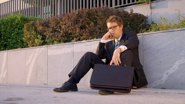 Anxious Caucasian yuppie sits on the side of the road after having a bad day. — Stock Photo, Image