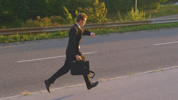 Cinematic shot of a young businessman running to work on a sunny summer morning. — Stock Photo, Image