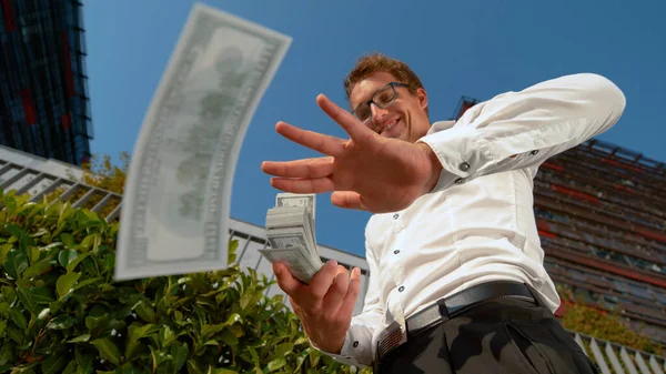 CLOSE UP: Businessman celebrates getting his first paycheck by making it rain.