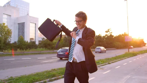 CLOSE UP: Безтурботний бізнесмен танцює по асфальтовому тротуару в сонячний вечір . — стокове фото