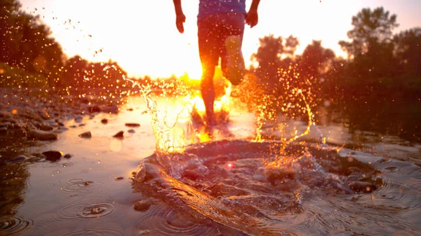 SUN FLARE CHIUDI: L'uomo atletico corre nel ruscello poco profondo verso il tramonto. — Foto Stock