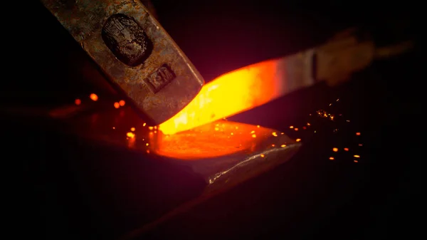 MACRO: Pequenas partículas pretas voando para longe da lâmina vermelha quente enquanto são forjadas — Fotografia de Stock