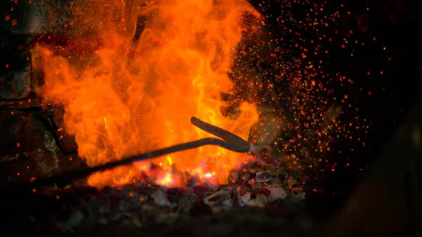 MACRO: Lange metalen poker roert de gloeiende vlammen in een grote bakstenen oven. — Stockfoto