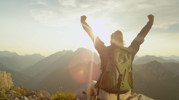 LENS FLARE: Trekker celebrates reaching mountaintop on a sunny summer day.
