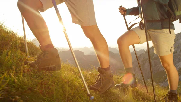 CERRAR: excursionistas irreconocibles con botas de cuero caminando por una colina cubierta de hierba . — Foto de Stock