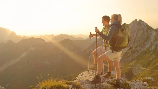 SOLE FLARE: Giovane coppia in piedi sulla cima della montagna e guardando il tramonto. — Foto Stock