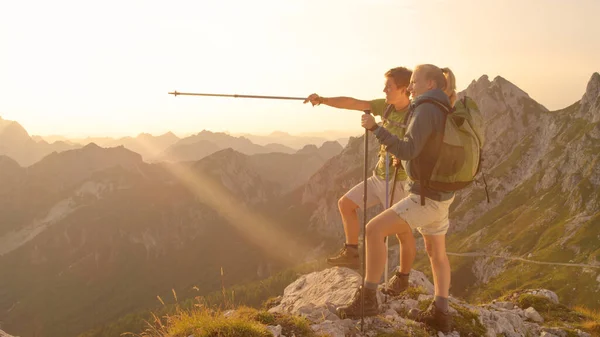 LENS FLARE: coppia attiva osserva il tramonto da una vetta delle Alpi. — Foto Stock