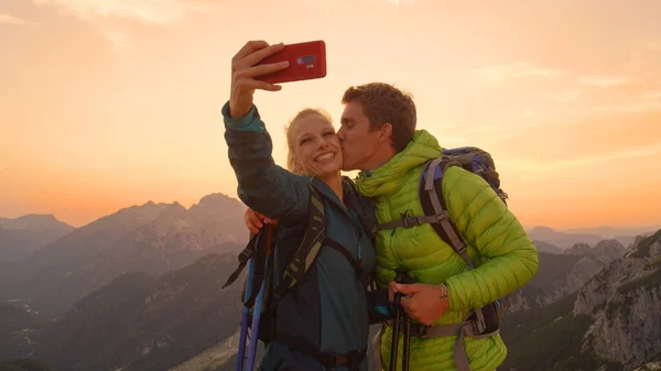 CLOSEUP: Man kisses his smiling girlfriend taking a photo of them in the Alps. — Foto de Stock