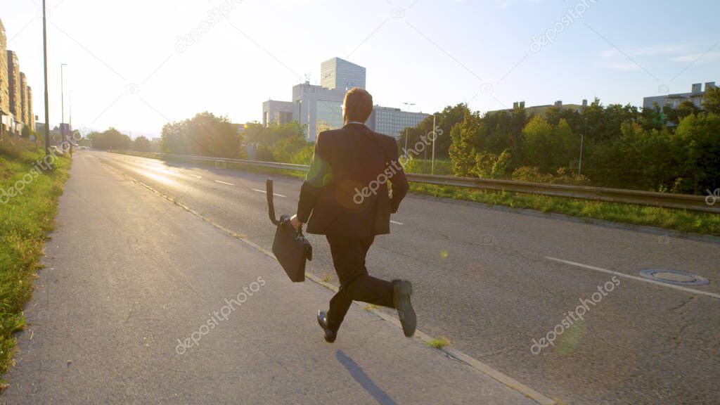 LENS FLARE: Unrecognizable businessman running to work on a sunny spring morning