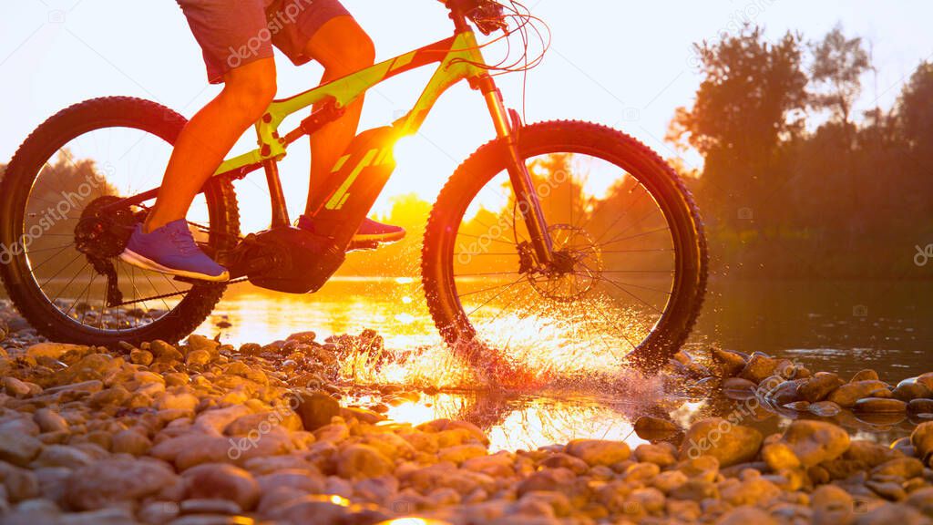 TIME REMAP: Cool shot of mountain biker riding across a river on golden morning.