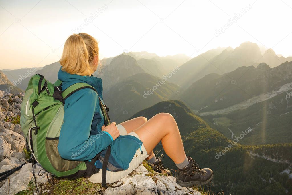 LENS FLARE: Unrecognizable trekker girl relaxing in picturesque sunny mountains.