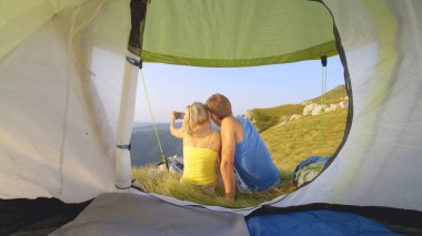 CLOSE UP: Unrecognizable couple cuddling and taking selfies in the calm Alps.