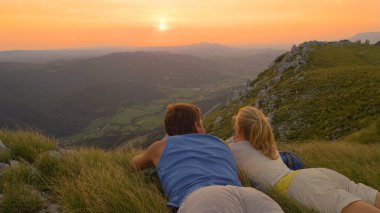 CLOSE UP Cheerful man and woman on active date watch the beautiful summer sunset