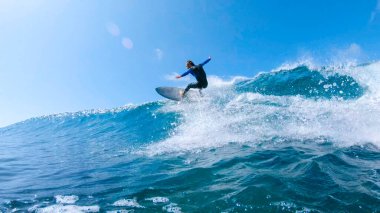 LOW ANGLE, LENS FLARE: Cheerful surfer riding big ocean wave in sunny nature. clipart