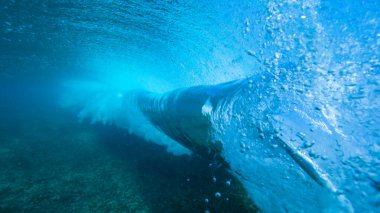 UNDERWATER: Beautiful deep blue tube wave rolls over the submerged camera.