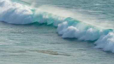 Crystal clear smooth waves slowly approaching empty coast from a great distance.