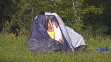 Happy Caucasian couple having fun preparing their tent during camping adventure