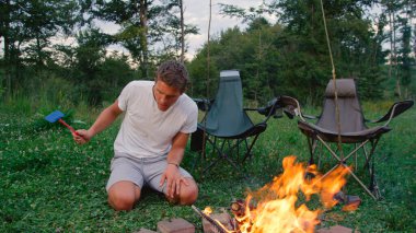 CLOSE UP: Man on camping trip flailing a fly swatter as he tries to kill a bug.